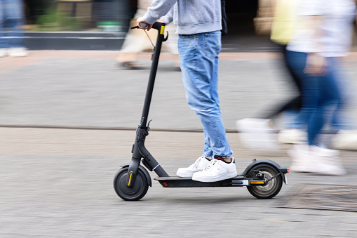 picture with intentional motion blur effect of a young person with a kick scooter in a pedestrian area