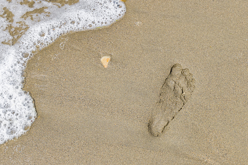A foot print of a person on a remote beach with sea in the background