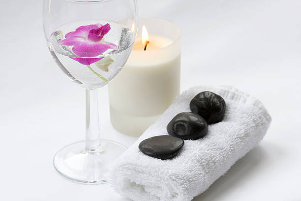 Massage stones and Pink Orchid in glass of water stock photo