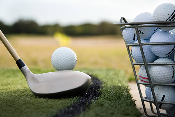 Driving range practice Close up of a golf club preparing to hit a  practice golf ball at a driving range.      bucket photos stock pictures, royalty-free photos & images