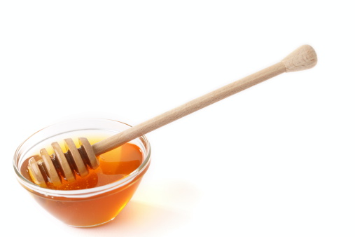 Honey in dish with honey dripper on white