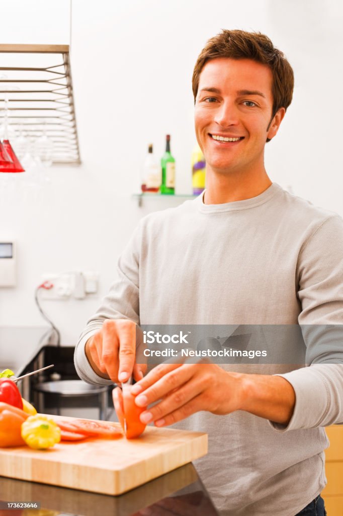 Retrato de un sonriente Joven hombre Cortando las verduras en la cocina - Foto de stock de 20-24 años libre de derechos