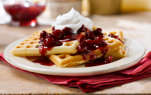 Golden Waffle with a rich berry sauce.  Shallow depth of field to isolate the subject.