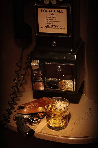 film-noir-phone booth-scotch und holstered revolver - film noir style telephone booth gun whisky stock-fotos und bilder