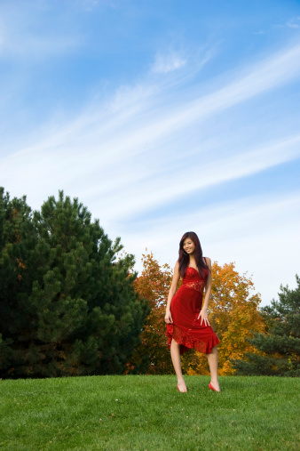 A woman in a red dress outdoors on an autumn day.