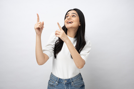 Portrait of young Indian woman pointing finger empty space isolated over white background