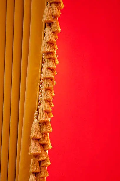 Fringed velvet drape hangs against bright red wall.