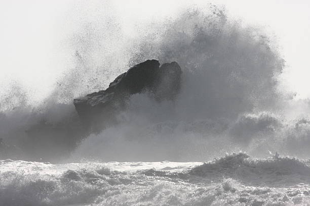 Ocean Wave Crashes Rock Coast Surf Spray Raging ocean surf slams Mavericks Beach rock with sunshine backlit spray flying 25 feet into air creating stunning high key effect.  Half Moon Bay, California, 2008. mavericks california stock pictures, royalty-free photos & images