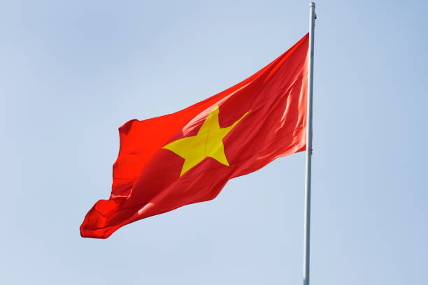 Subject: The flag of Vietnam waving in the breeze under a clear sky.