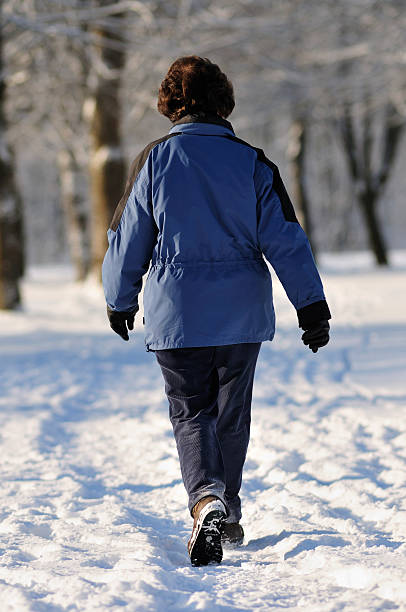 istock old woman walking in winter avenue 173632610