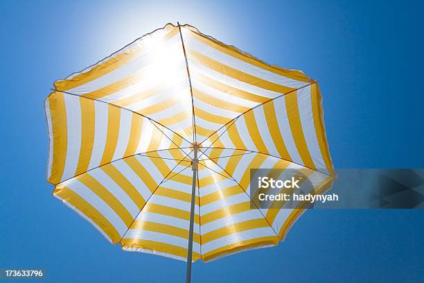 Foto de Guardasóis Amarelos Contra O Sol E Céu Azul e mais fotos de stock de Abaixo - Abaixo, Guarda-sol, Amarelo