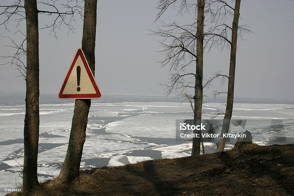 Cautiously, glaciers! There has come spring. Ice started to thaw from the river.On the tree sign - symbol of danger hangs. Canal Stock Photo