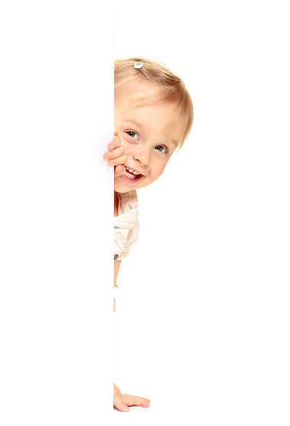 Little girl peeking from behind the advert. stock photo