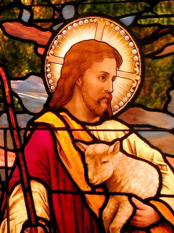 A detail photo of a stained glass window picturing Jesus holding a lamb.