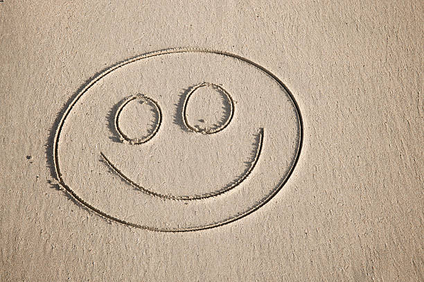 Simple happy face with wide eyes in textured sand