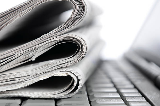 Morning news, folded newspapers lying on notebook keyboard, monochrome