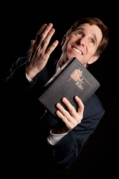 An African-American male praying with his head down looking at the Bible at the church