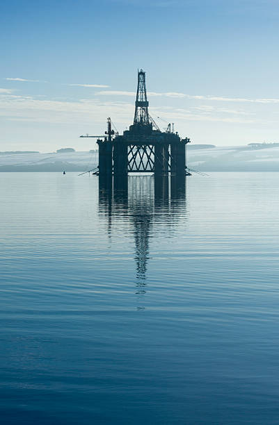 An oil rig in the middle of a body of water  stock photo