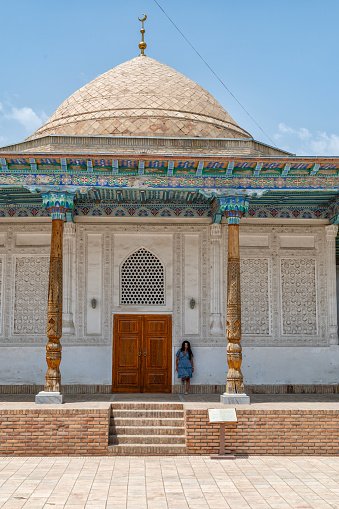 A lady standing in front of the Abdushakur Agalik Madrasa in Shahrisabz, beautiful building in typical style of Uzbekistan