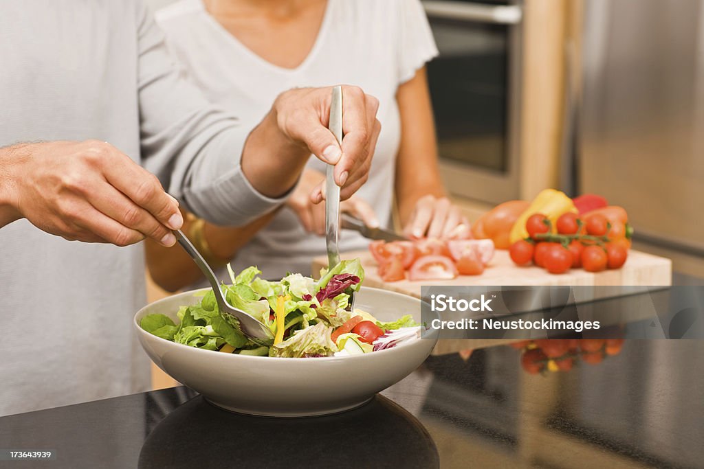 男性と女性のサラダを備えたキッチン - まな板のロイヤリティフリーストックフォト