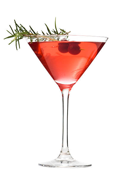 Martini Glass of Cosmopolitan Cocktail, Red Alcoholic Beverage on White A red cranberry cosmopolitan with a sprig of rosemary in a martini glass. The festive alcoholic beverage is isolated on a white background. fruit garnish stock pictures, royalty-free photos & images