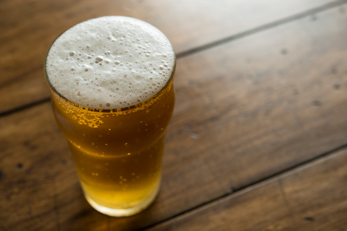 pint of Lager, shallow focus, against aged wood background.