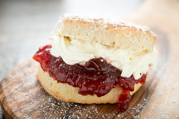 Cream Scone A slightly messy indulgent Fresh Cream Scone with Strawberry Jam. scone photos stock pictures, royalty-free photos & images