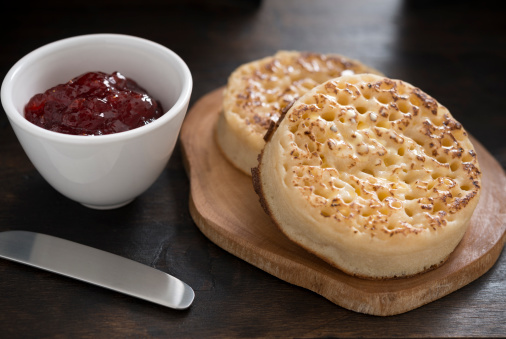 Toasted buttered Crumpets with pot of strawberry jam.