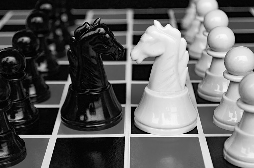 Selective view of knight chess moving toward for battle with black and white background. Strategy and tactic concept.