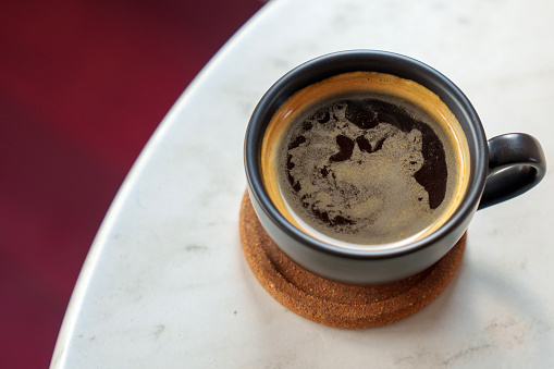 View of Turkish coffee and traditional cup. Turkish coffee is a style of coffee prepared using very finely ground coffee beans without filtering. Despite the name, the style originated in Yemen.