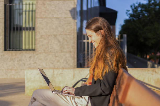 istock Happy casual woman using laptop sitting on a bench 1736579674
