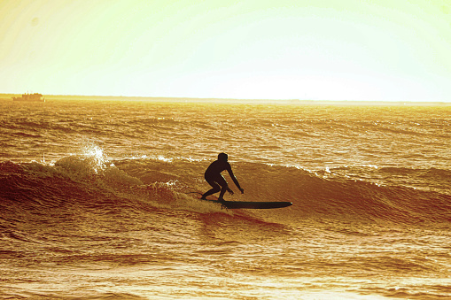 An image of an unrecognizable long-boarder in silhouette in Seal Beach, California.