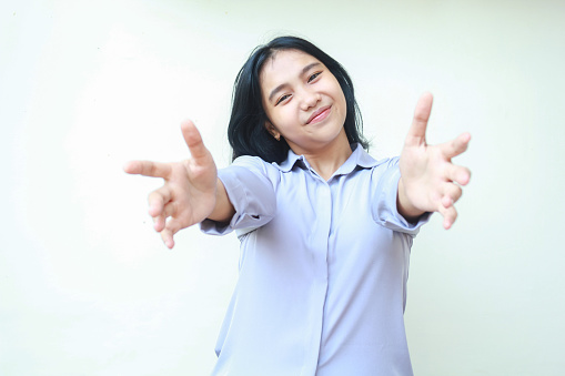 friendly asian young business woman reaching hands towards camera with smiling face welcoming you wearing formal shirt isolated on white background