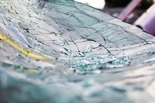 A closeup view of a broken vehicle windshield.