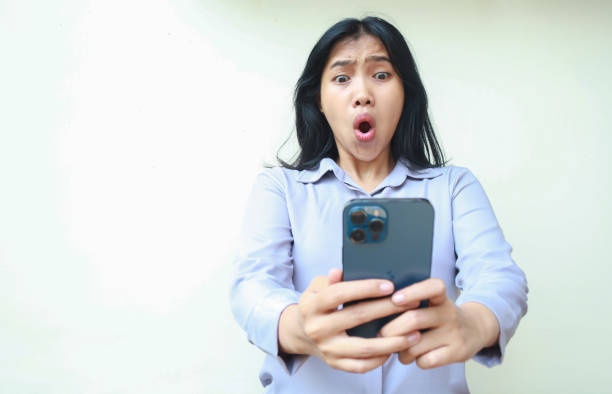istock amazed asian young business woman using smartphone shocked with wow expression wearing formal shirt standing over isolated white background 1736597051