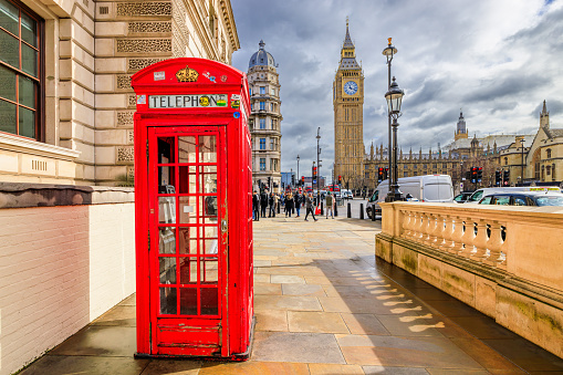 London, England, UK - March 14, 2023: The red telephone booth and Big Ben Clock Tower in the background.