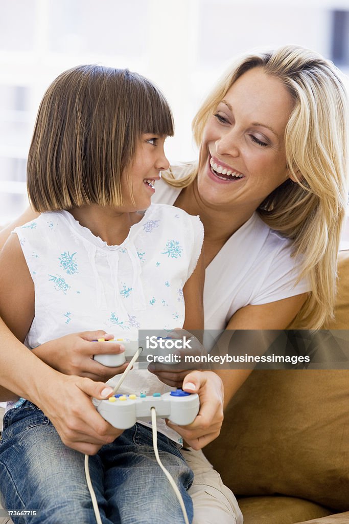 Donna e ragazza in salotto con controller video gioco - Foto stock royalty-free di Accogliente