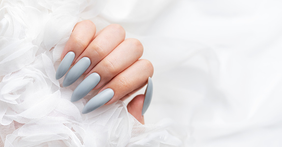 Womans hands with trendy manicure on blue background. Summer nail design. Beauty salon concept