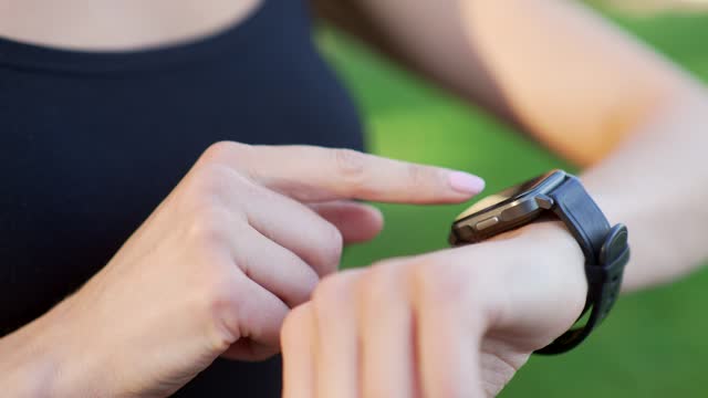 Close up of a female hand with a smart watch. Sportswoman uses a fitness tracker, scrolls her finger on touch screen,