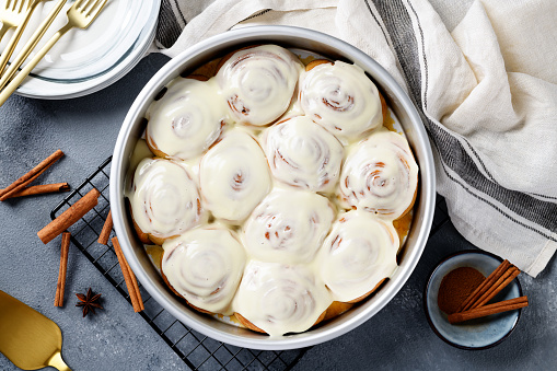 Homemade cinnamon buns with cream cheese icing in backing pan. top view