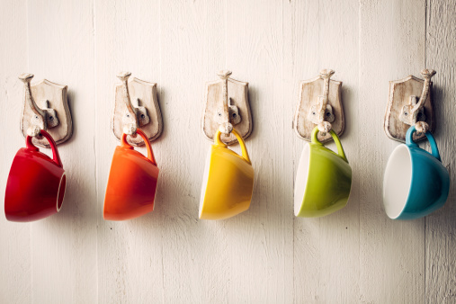 Colorful coffee cups on hooks