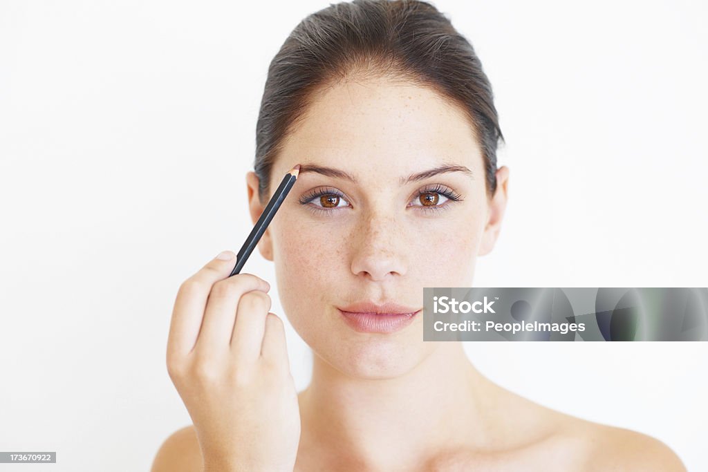 Putting my face on An attractive young woman using an eye pencil on her eye brows Eyebrow Pencil Stock Photo
