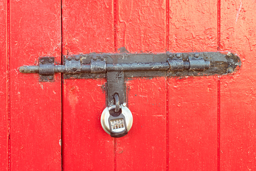 Combination lock locking a steel bolt lock on a double door shed barn workshop