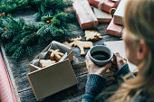 A woman drinks coffee and wraps Christmas gifts.