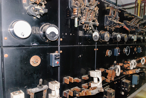 Very old electrical switchgear with gauges and Edison style knife switches in an abandoned factory.