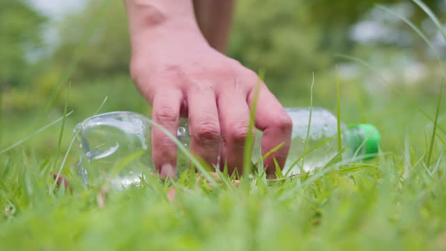 Hand a man picking plastic bottles blank on green grass