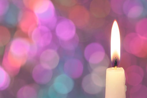 Three burning candles on a decorated column