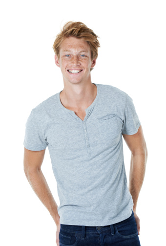 A handsome young red-headed man in casual attire posing against a white background