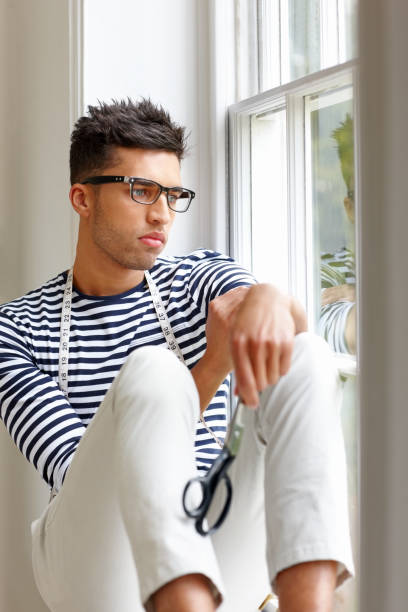 istock Young male dressmaker sitting by a window day dreaming 173675450