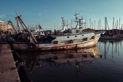 Civitavecchia, Italy, October 9, 2023: Fishing boats docked at the harbor on October 9, 2023 in Civitavecchia, Italy. The boats just landed fish, at sunset, after a day of fishing activity.